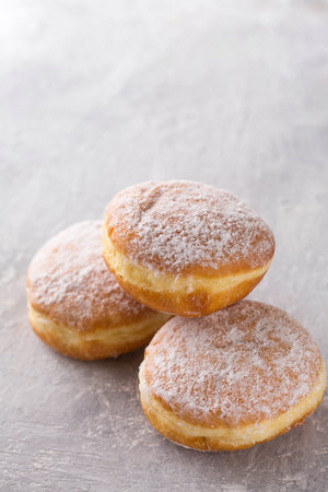 Ruddy delicious donuts berliners with filling sprinkled with powdered sugar on a gray backgroundの写真素材