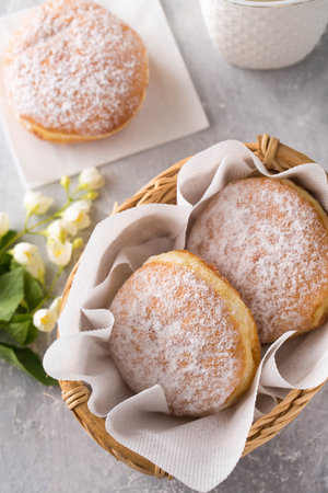 Ruddy delicious donuts berliners with filling sprinkled with powdered sugar in basket on a gray backgroundの写真素材