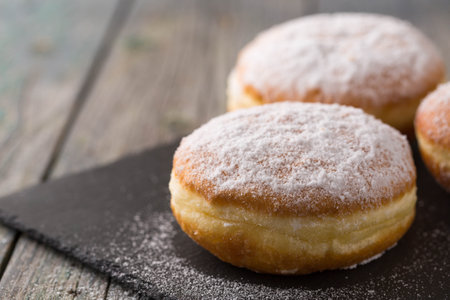 Ruddy delicious donuts berliners with filling sprinkled with powdered sugar on a rustic backgroundの写真素材