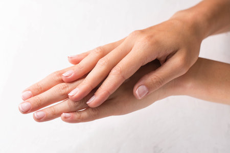Female hands with minimalist french manicure on white backgroundの写真素材