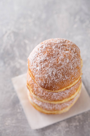 Ruddy delicious donuts berliners with filling sprinkled with powdered sugar on a gray backgroundの写真素材