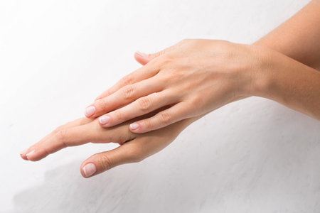 Female hands with minimalist french manicure on white backgroundの写真素材