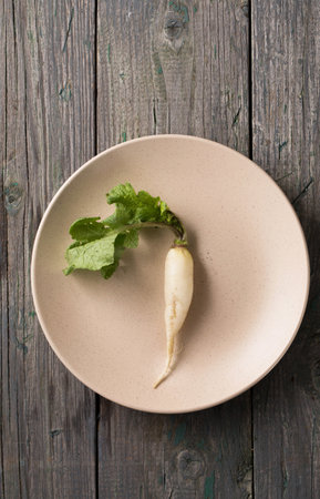 Fresh, white, long radish with leaves on a wooden boardの写真素材