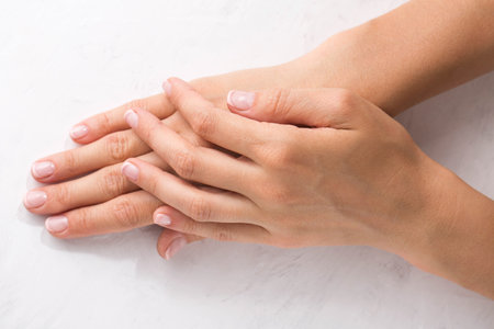 Female hands with minimalist french manicure on white backgroundの写真素材