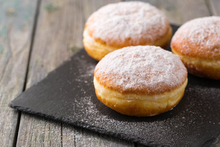 Ruddy delicious donuts berliners with filling sprinkled with powdered sugar on a rustic backgroundの写真素材