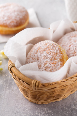 Ruddy delicious donuts berliners with filling sprinkled with powdered sugar in basket on a gray backgroundの写真素材