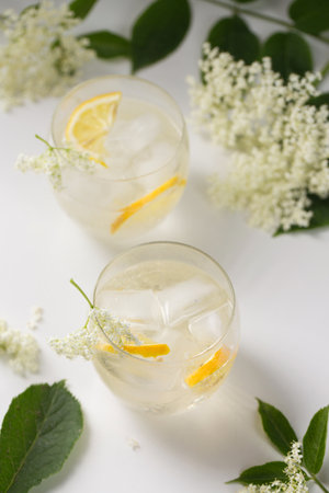 A delicious cold summer drink made of elderflowers and lemon with ice on a light backgroundの写真素材