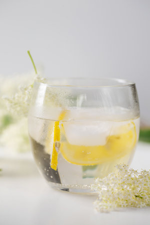 A delicious cold summer drink made of elderflowers and lemon with ice on a light backgroundの写真素材