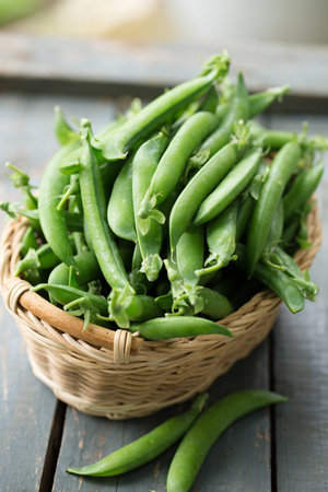 Ripe fresh green peas in a wicker basket on a rustic backgroundの写真素材