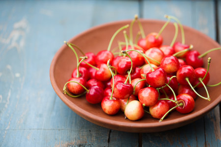 A ripe sweet cherry in a ceramic bowl on a rustic backgroundの写真素材
