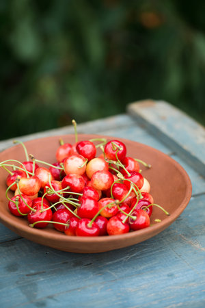 A ripe sweet cherry in a ceramic bowl on a rustic backgroundの写真素材