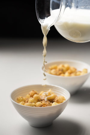 Breakfast cereal with granola and corn rings in small bowls on a white background