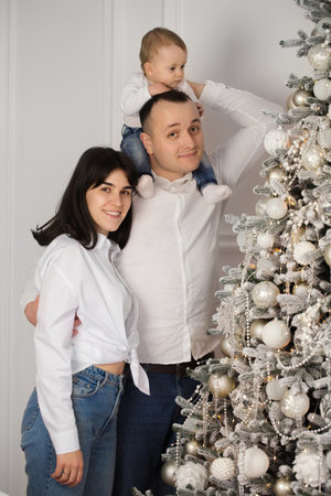 Happy young married couple with a small child near the Christmas treeの写真素材
