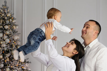 Happy young married couple with a small child near the Christmas treeの写真素材