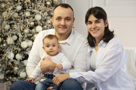 Happy young married couple with a small child near the Christmas treeの写真素材