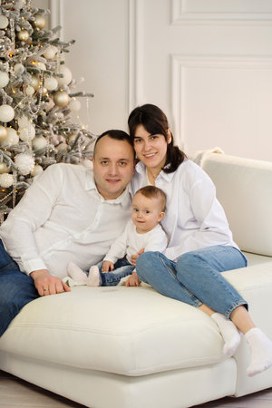 Happy young married couple with a small child near the Christmas treeの写真素材