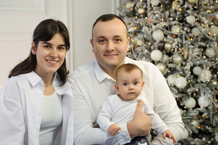 Happy young married couple with a small child near the Christmas treeの写真素材