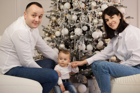 Happy young married couple with a small child near the Christmas treeの写真素材