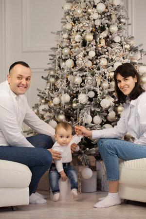 Happy young married couple with a small child near the Christmas treeの写真素材