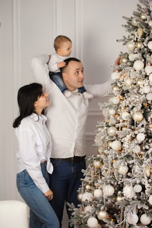 Happy young married couple with a small child near the Christmas treeの写真素材