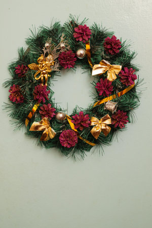 Christmas wreath with pine cones and golden bows in vintage style on a gray backgroundの写真素材