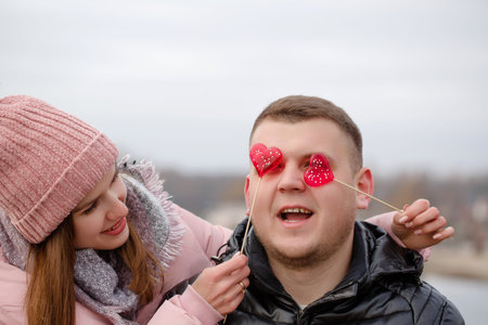 Young beautiful woman with red sweets on a stick in hands. Valentine's day concept