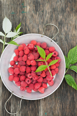 Ripe raspberries in a vintage sieve on an old wooden backgroundの写真素材