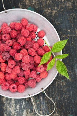 Ripe raspberries in a vintage sieve on an old wooden backgroundの写真素材