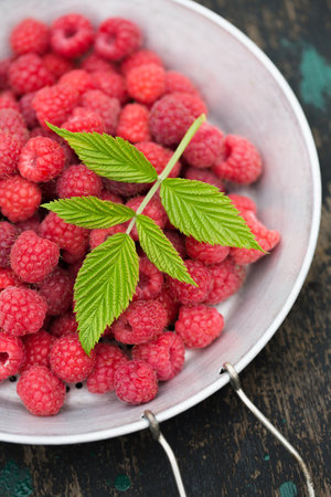 Ripe raspberries in a vintage sieve on an old wooden backgroundの写真素材