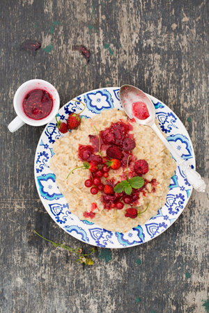 Quick breakfast of oatmeal and berries in a white bowlの写真素材