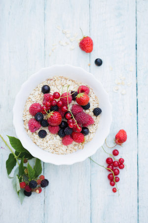 Quick breakfast of oatmeal and berries in a white bowlの写真素材
