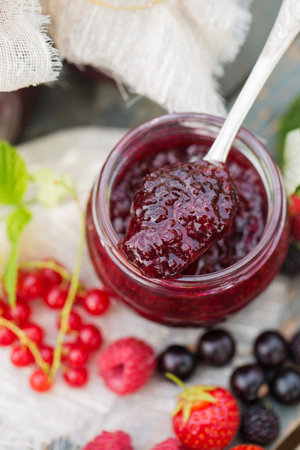 Delicious berry jam in a jar in the summer garden
