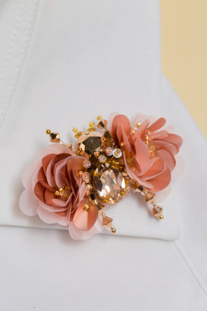 Handmade brooch beetle made of stones and sequins on the collar of a white shirt on a beige backgroundの写真素材