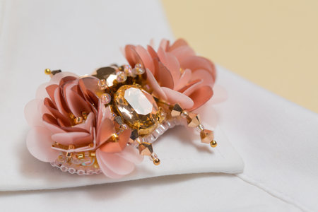 Handmade brooch made of stones and sequins on the collar of a white shirt on a beige backgroundの写真素材