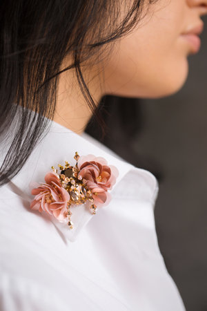 A beautiful pink handmade brooch on a woman's shirt collar, close-upの写真素材