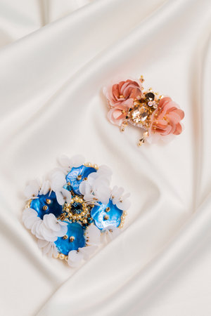 Handmade blue mother-of-pearl brooch on white silk fabric, close-upの写真素材