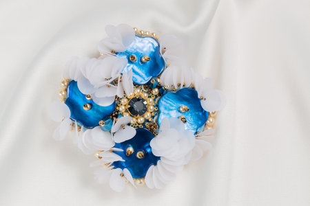 Handmade blue mother-of-pearl brooch on a white cloth, close-upの写真素材