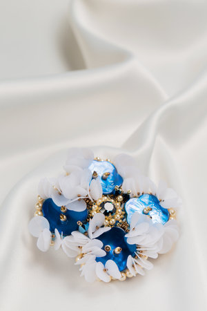 Handmade blue mother-of-pearl brooch on a white cloth, close-upの写真素材