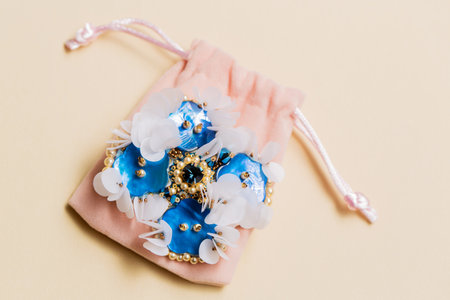 Handmade blue mother-of-pearl brooch on a plush bag on a beige backgroundの写真素材