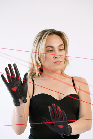 An adult woman in black gloves with a heart with red threads. The concept of hopelessnessの写真素材