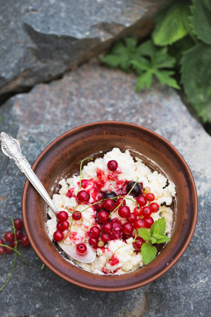 Summer breakfast of homemade cottage cheese and red current berries in the gardenの写真素材