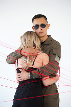 A young couple, a man and a woman, are wrapped in red threads. Dependency concept and unityの写真素材