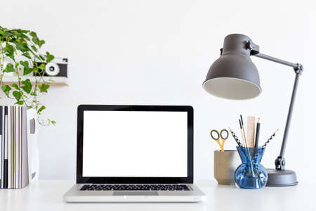 Cropped shot of modern workspace with blank screen laptop, stationery and decorations on white tableの写真素材