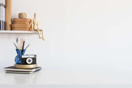Cropped shot of minimal workspace with books, camera and stationery on white tableの写真素材
