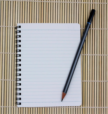 blank realistic spiral notepad notebook with pencil on brown bamboo background