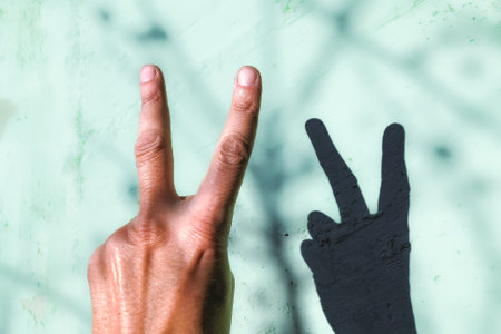Hand of man showing victory sign on the grunge wall background.の写真素材