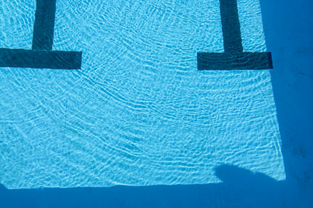 Swimming pool with blue water and sun reflection. Background and textureの写真素材