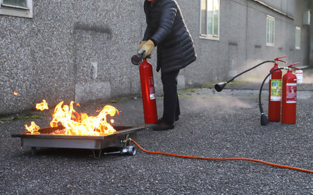 Firefighter extinguishing a fire with a fire extinguisher on the streetの写真素材