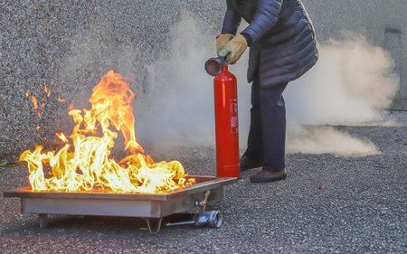 Firefighter using fire extinguisher to extinguish a fire on the street