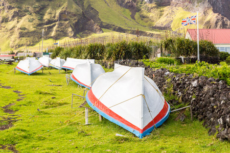 Countryside grass street with a row of drying overturned boats. British Governor flag flying. Edinburgh of the Seven Seas town, Tristan da Cunha, the most remote inhabited island, South Atlantic Oceanの写真素材
